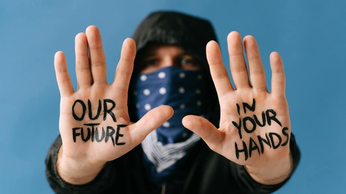Close-up of hands displaying a powerful protest message "Our future in your hands."