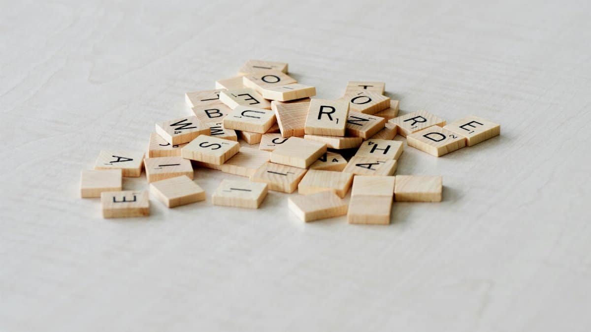 Close-up of wooden letter tiles scattered on a light table surface, ideal for word games.