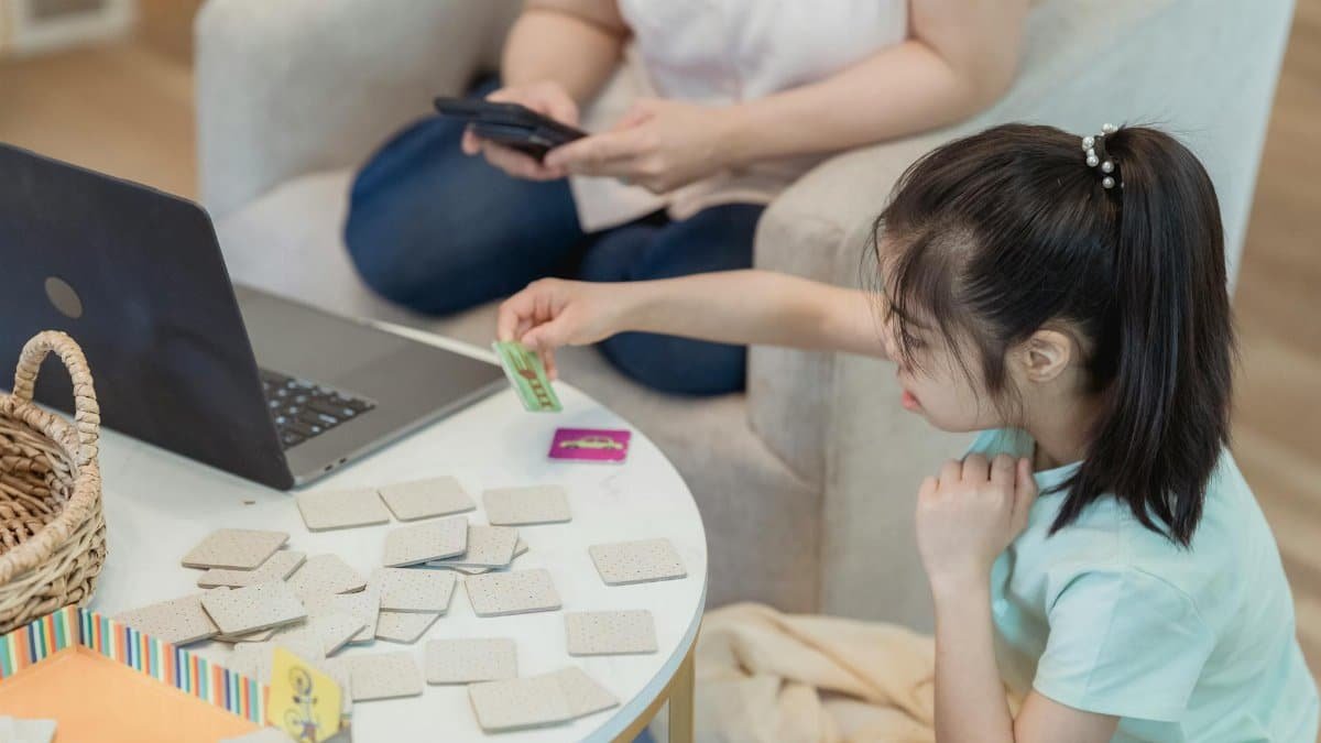 Asian girl focused on memory game at home with cards, enhancing cognitive skills.
