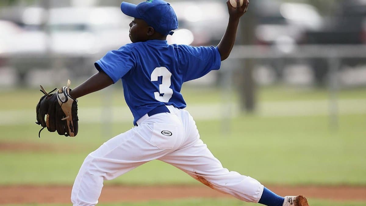 Young player pitching in a youth baseball game on a sunny day.