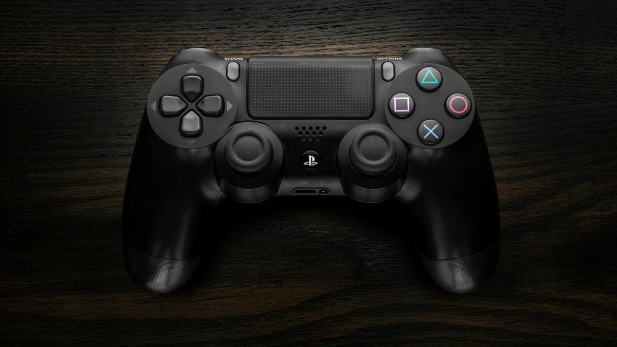 High-resolution image of a Sony DualShock 4 game controller against a dark wooden background.