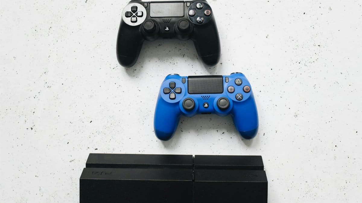 Two game controllers placed on a white surface above a gaming console.