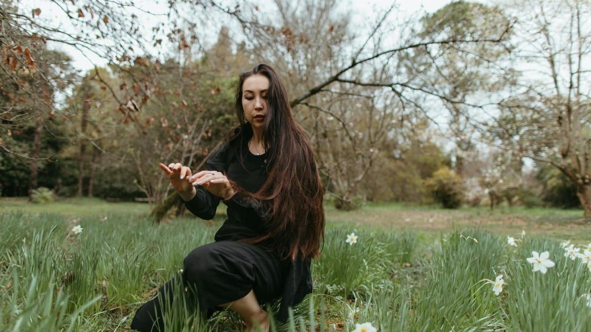 A woman practices meditation and mindfulness surrounded by a peaceful meadow.