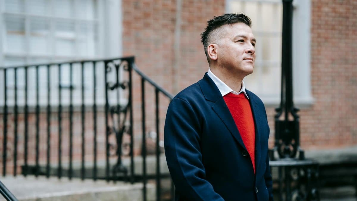 A fashionable man confidently poses outdoors in classic attire, exuding confidence and style.