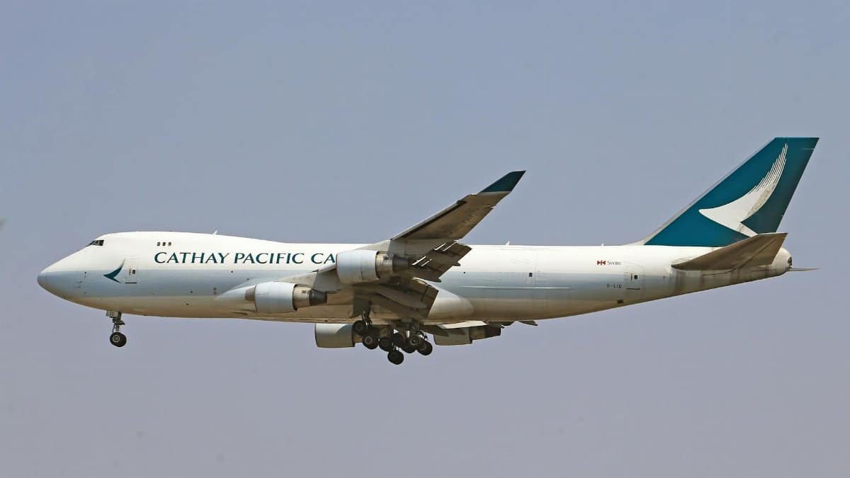Cathay Pacific cargo plane mid-air with landing gear, side view.