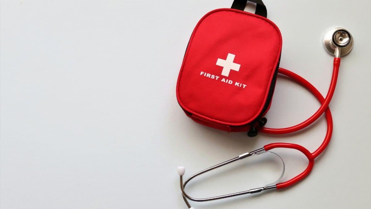 Red first aid kit and stethoscope on a white surface, ideal for healthcare themes.