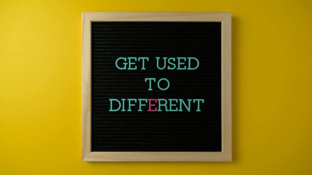 Letter board with 'Get Used To Different' message on vibrant yellow background.