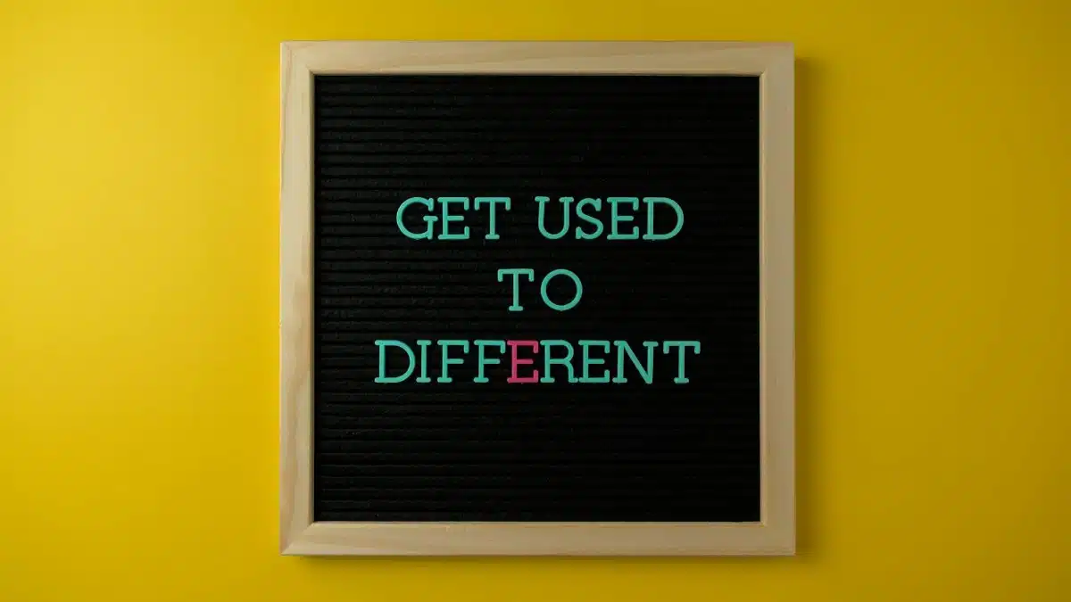 Letter board with 'Get Used To Different' message on vibrant yellow background.