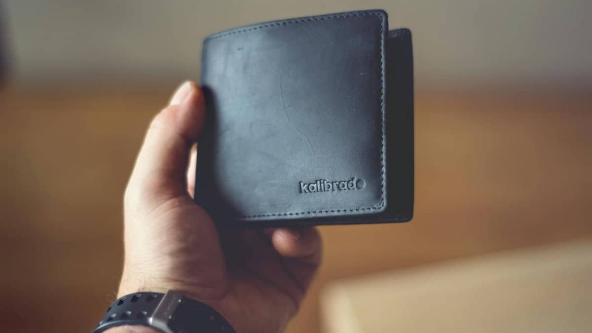 Close-up of a stylish black leather wallet held by a person, showcasing design.