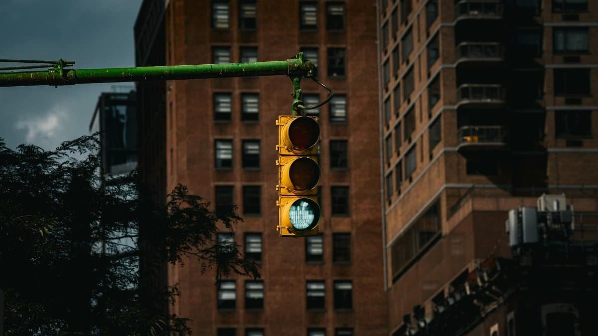 Classic New York traffic light with green signal in front of urban buildings.