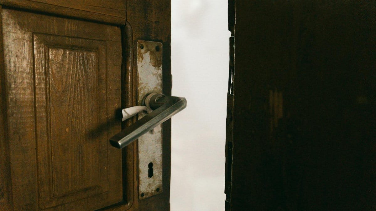 A rustic wooden door slightly ajar with a metal handle, creating a mysterious ambiance.