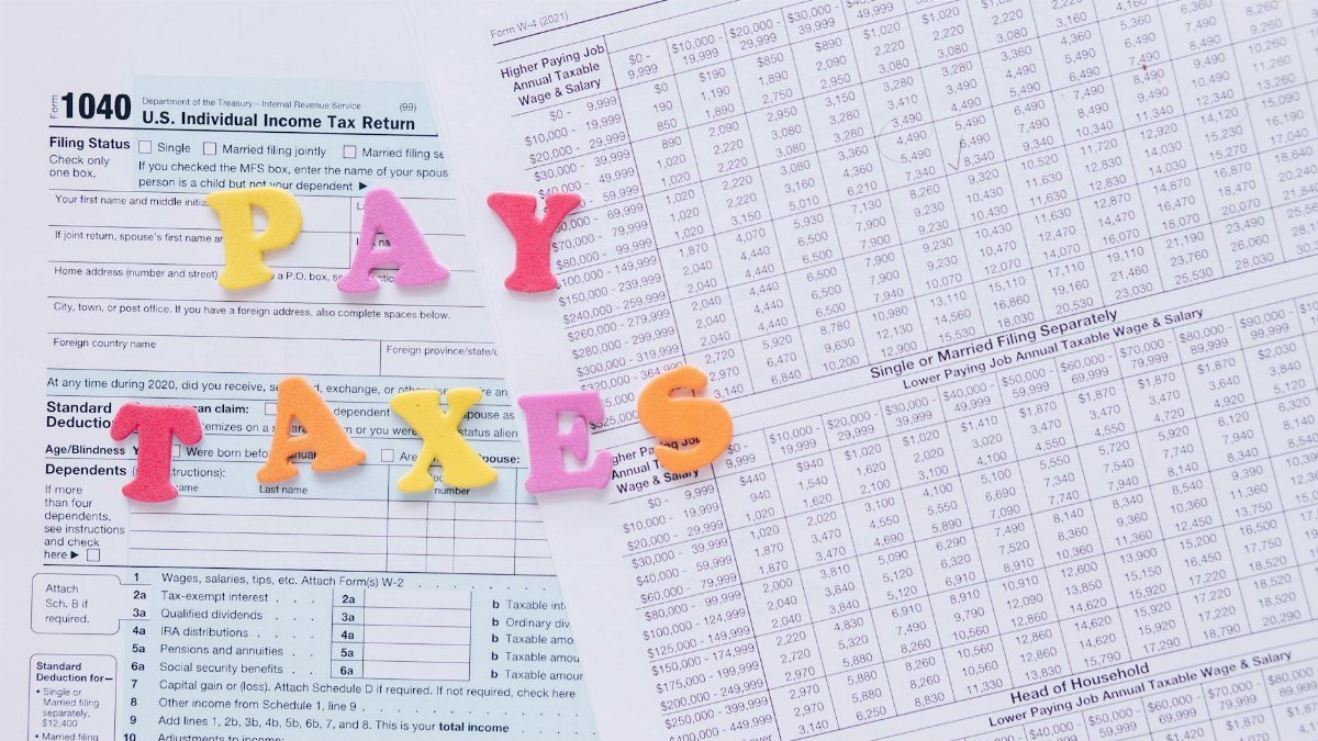 Close-up of U.S. tax forms with colorful 'PAY TAXES' letters emphasizing financial deadlines.