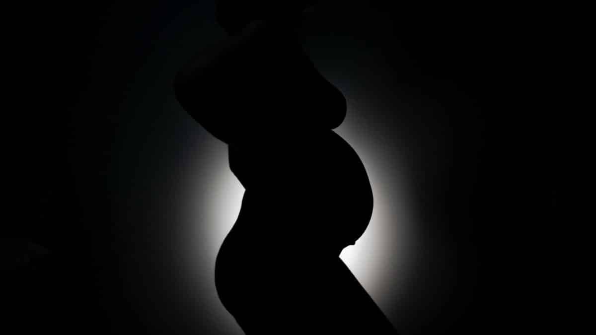 Artistic silhouette of a pregnant woman highlighting maternal beauty against a dark background.