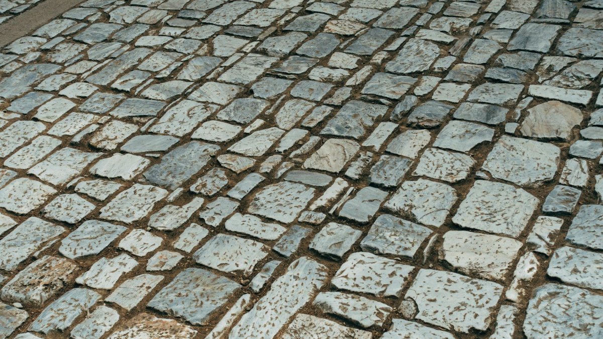 Old cobblestone path featuring granite stones in a classic pattern, offering a textured surface view.