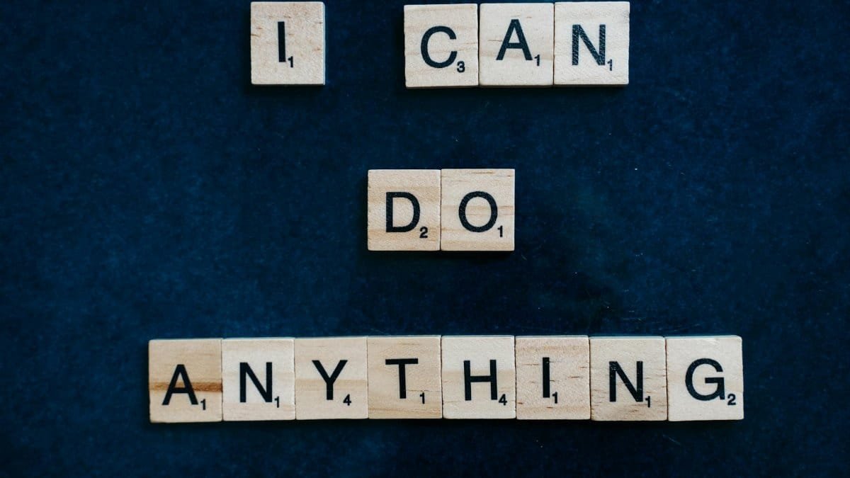Inspirational phrase 'I Can Do Anything' created with Scrabble tiles on a blue surface.