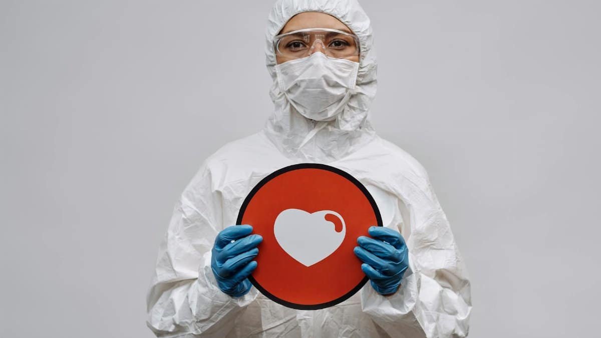Individual in protective gear holding a heart symbol sign conveying care and protection.