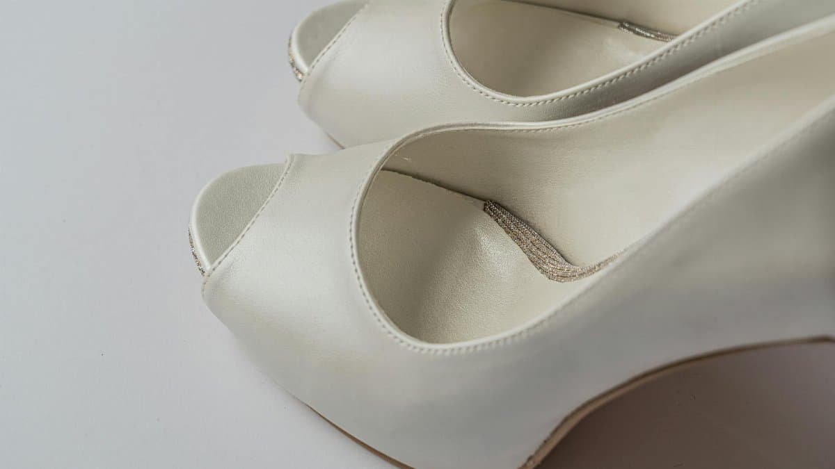 Close-up of elegant white peep-toe high heels on a neutral background.