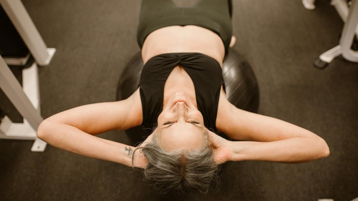 Senior woman performing exercise on stability ball for fitness and strength.
