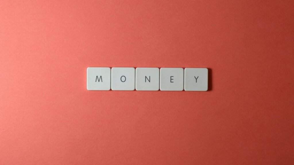 Minimalist layout showing word 'money' with letter tiles on a coral background.