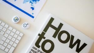 Stylish desk setup with a how-to book, keyboard, and world map on paper.