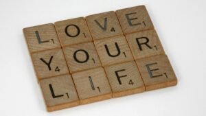 Scrabble tiles arranged to spell 'Love Your Life' against a white background, conveying a positive message.