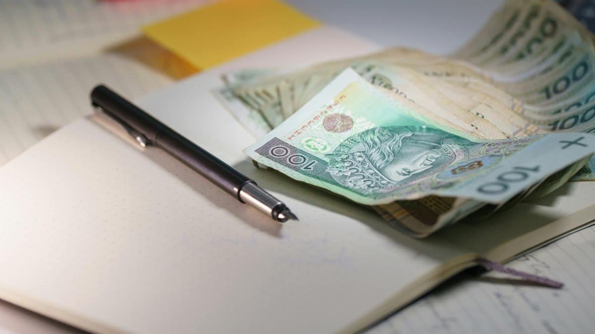Close-up of Polish Zloty banknotes on an open notebook with a pen, symbolizing finance and budgeting.