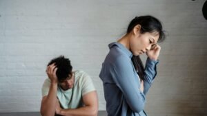 An Asian woman and man feeling misunderstood and frustrated in a relationship indoors.
