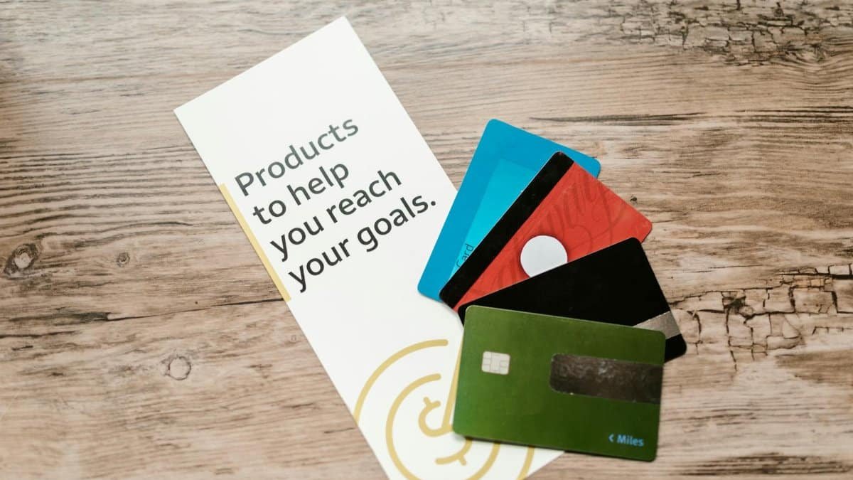 Assorted credit cards on a wooden table next to a leaflet with motivational text about financial goals.