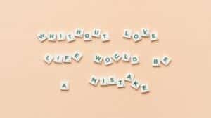 Scrabble tiles forming the phrase 'Without love life would be a mistake' on a beige background.
