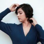 Serene portrait of a woman in a blue dress posing gracefully against white background.