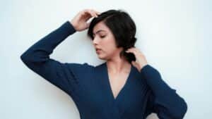 Serene portrait of a woman in a blue dress posing gracefully against white background.