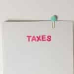 Close-up of a tax file with a pink 'TAXES' label and a paperclip, offering copy space and a conceptual minimalist design.