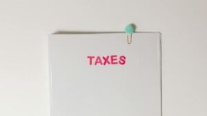 Close-up of a tax file with a pink 'TAXES' label and a paperclip, offering copy space and a conceptual minimalist design.