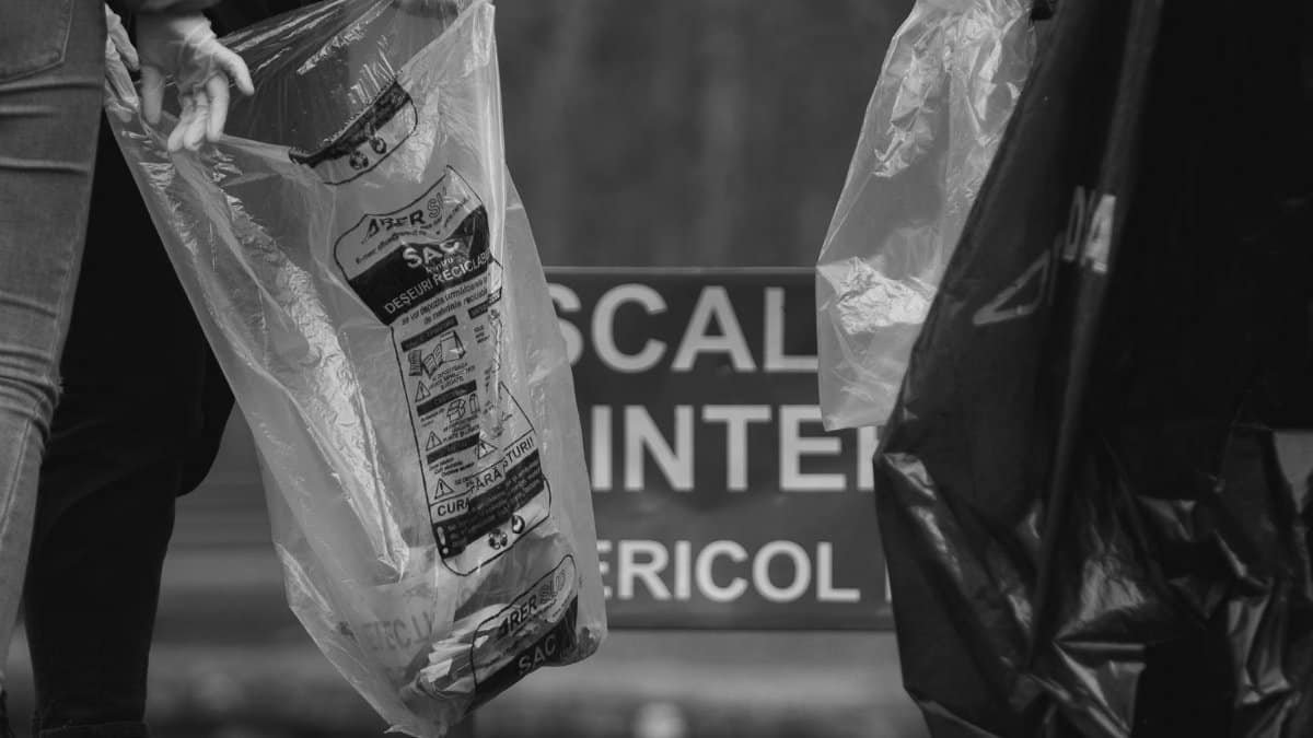 Group of people holding garbage bags during community cleanup in black and white.