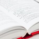 An open book with a red cover showing pages filled with text, symbolizing knowledge and education.