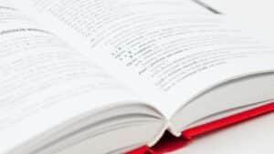 An open book with a red cover showing pages filled with text, symbolizing knowledge and education.