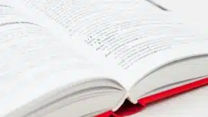 An open book with a red cover showing pages filled with text, symbolizing knowledge and education.