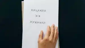 Hand holding paper with 'Balance or Burnout' text, promoting mental wellness.
