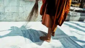 A Buddhist monk sweeping the marble courtyard in Bodhgaya, India. Captured in sunlight, highlighting spiritual simplicity.