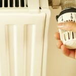Close-up of hand adjusting radiator thermostat to control home heating temperature.