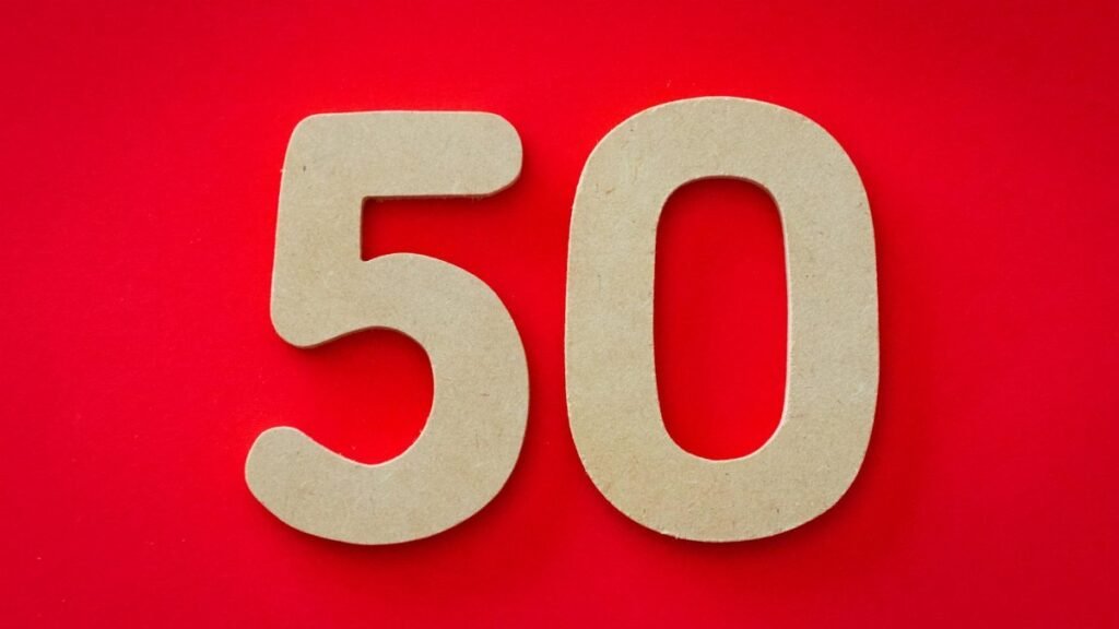 Close-up of cardboard cutout number 50 on a vivid red backdrop, symbolizing celebration or milestone.