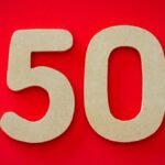 Close-up of cardboard cutout number 50 on a vivid red backdrop, symbolizing celebration or milestone.