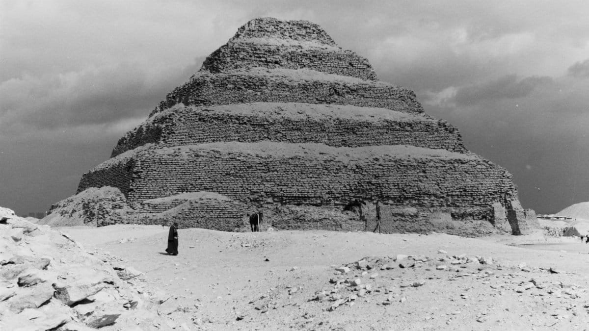 Monochrome photograph showcasing the Step Pyramid of Djoser under a dramatic sky in Egypt.