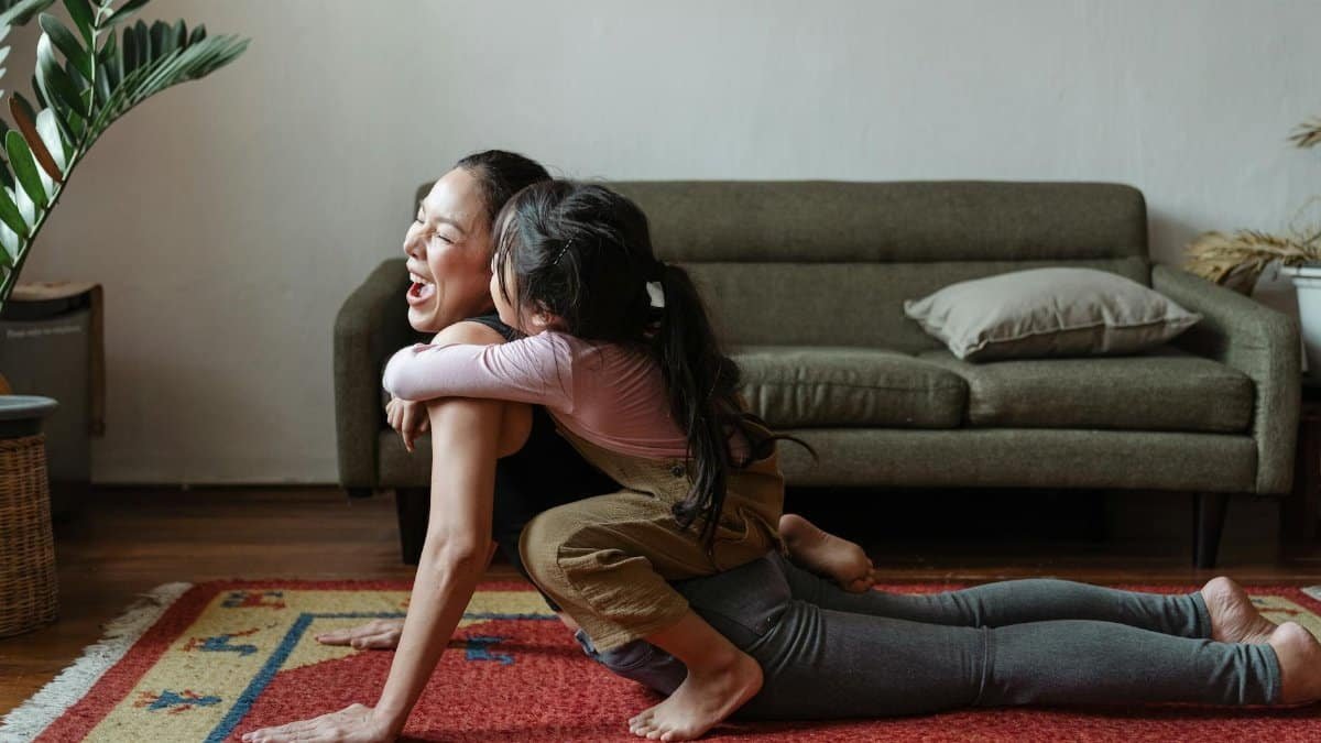 A cheerful mother and daughter bonding during a vibrant yoga session in a cozy living room.