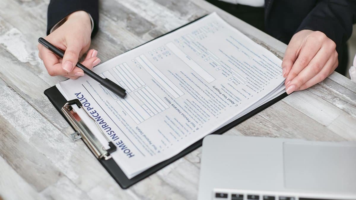Close-up of hands reviewing a home insurance policy, emphasizing professionalism and finance.