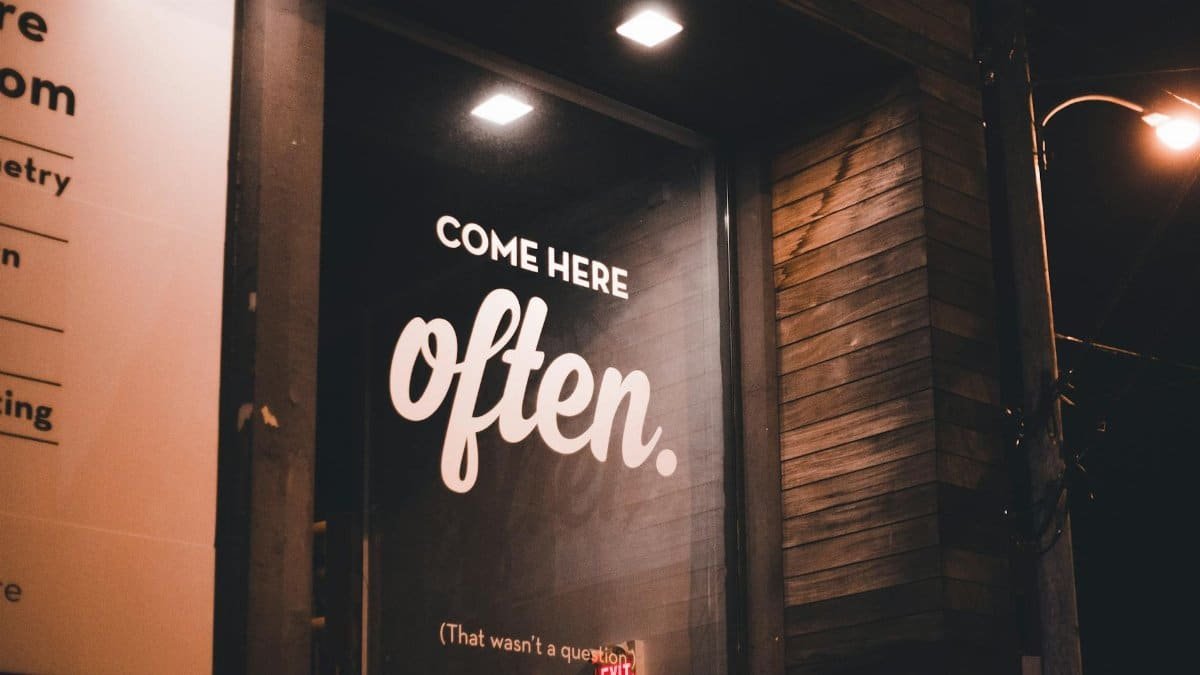 Cozy storefront at night with a welcoming illuminated sign 'Come Here Often.'