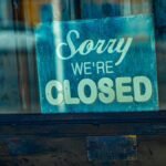 Retro 'Sorry We're Closed' sign displayed on a rustic glass door, depicting temporary closure.