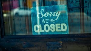 Retro 'Sorry We're Closed' sign displayed on a rustic glass door, depicting temporary closure.