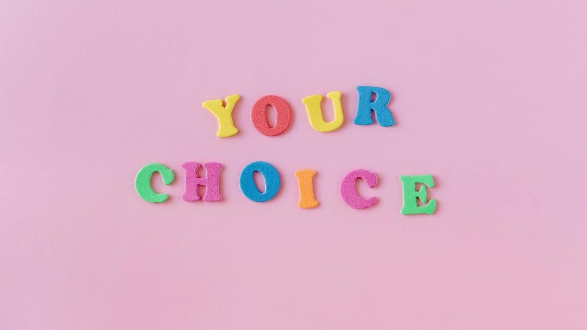Vibrant foam letters spelling 'YOUR CHOICE' on a pink background. Perfect for concepts of decision-making.