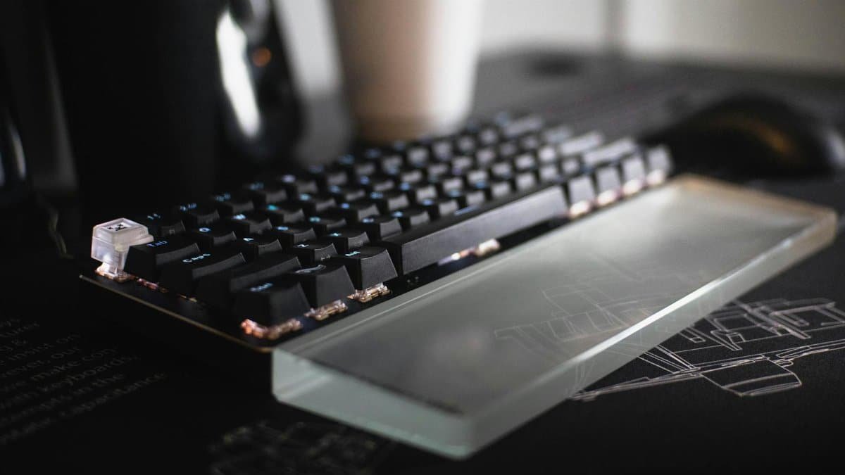 Close-up of a modern mechanical keyboard with a glass wrist rest, showcasing sleek design and innovation.